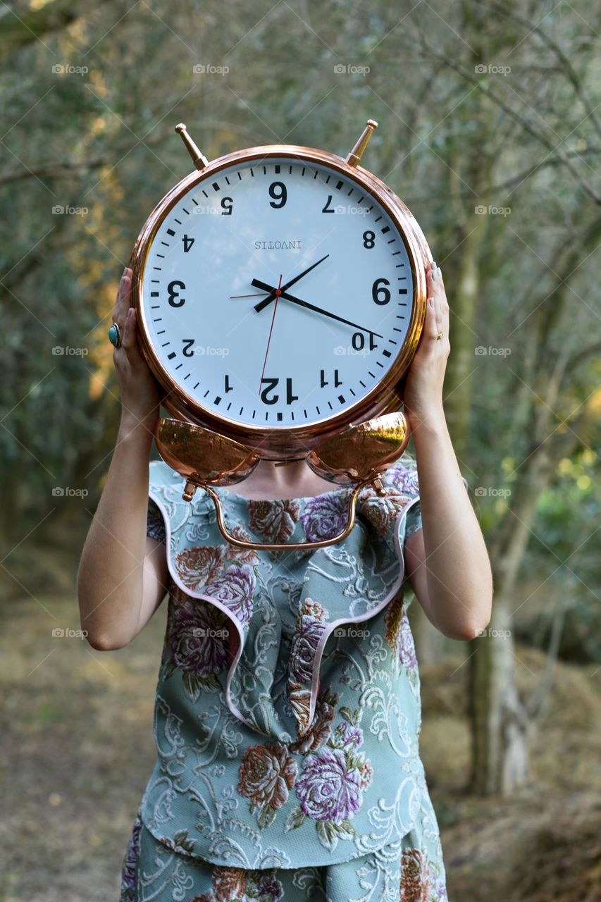 Outdoors female portrat with a clock in her heands