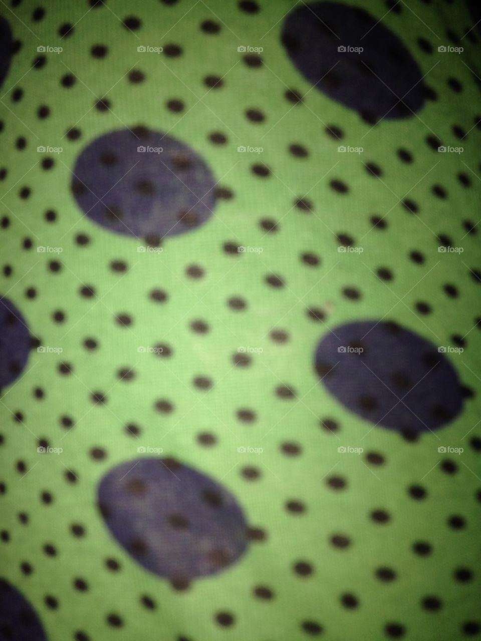Polka dotted green cloth with black and blue spots background texture
