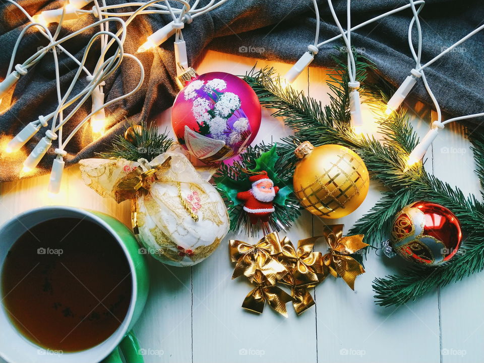 Christmas toys, a cup of hot tea and Christmas tree garland on a white table