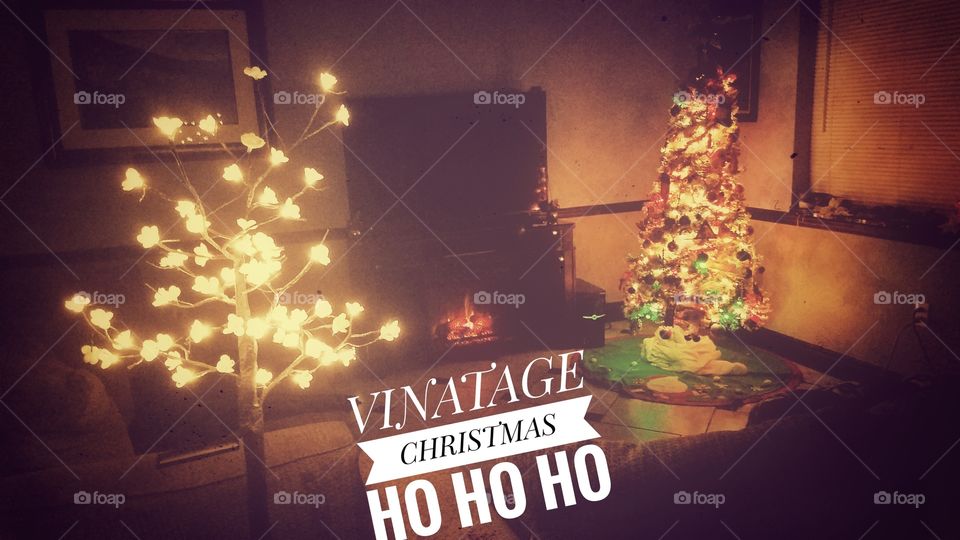A joyous vintage Christmas scene with a decorative tree and fireplace set in a warm living room with a lighted cherry blossom tree