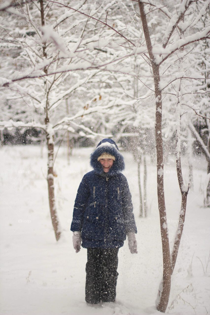 Girl rejoices in the snow falling from the tree