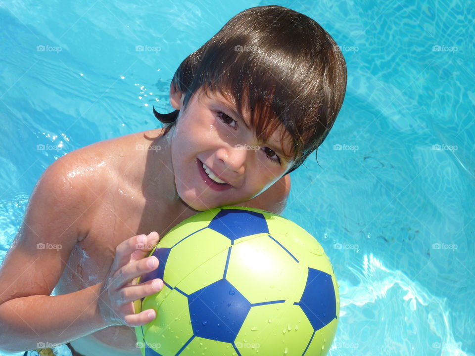 Boy play with a ball in swimming pool