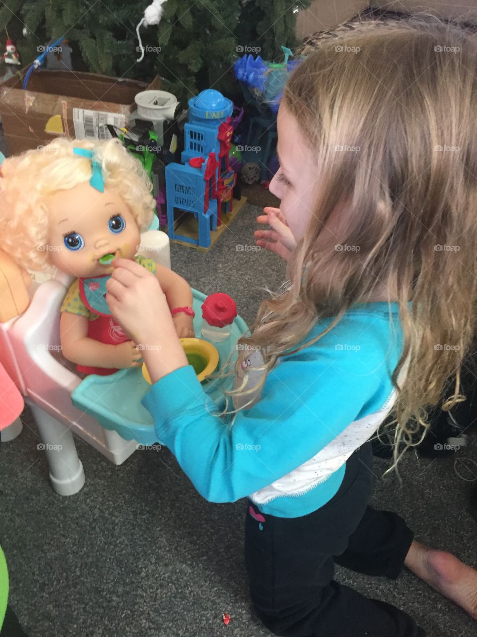 Little girl feeding her toy doll