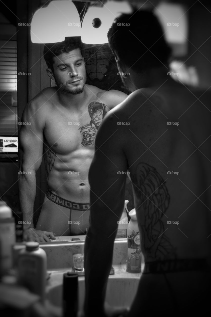 Reflection of shirtless young man on mirror