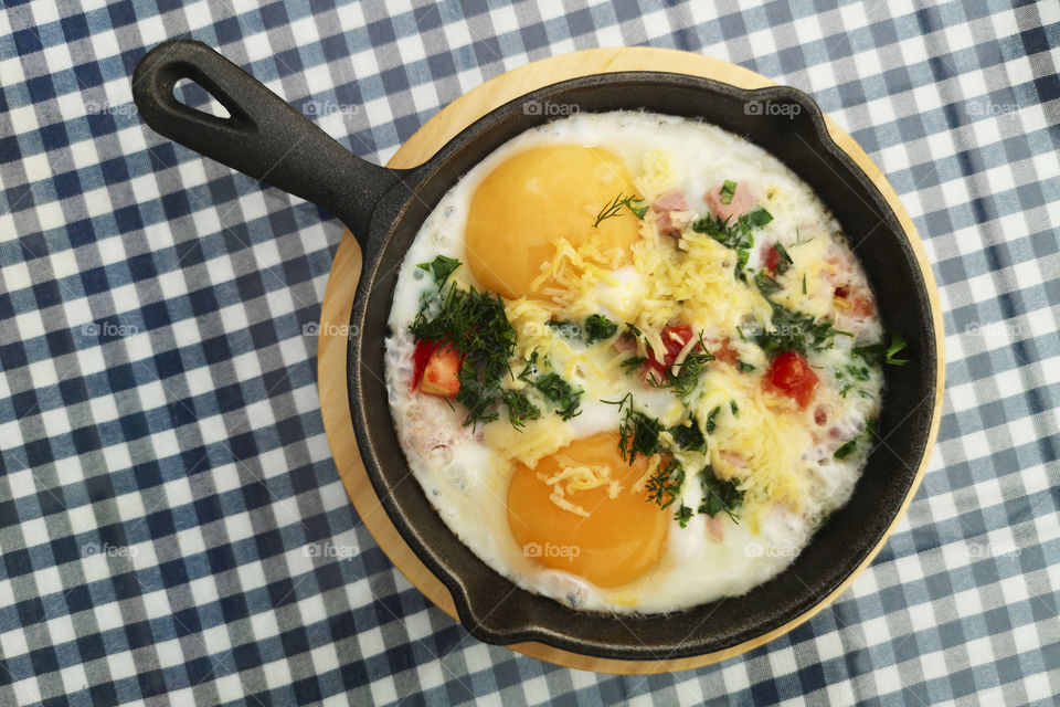 Fried eggs with onion and cheese in a frying pan. Freshly made, delicious meal of eggs and vegetables
