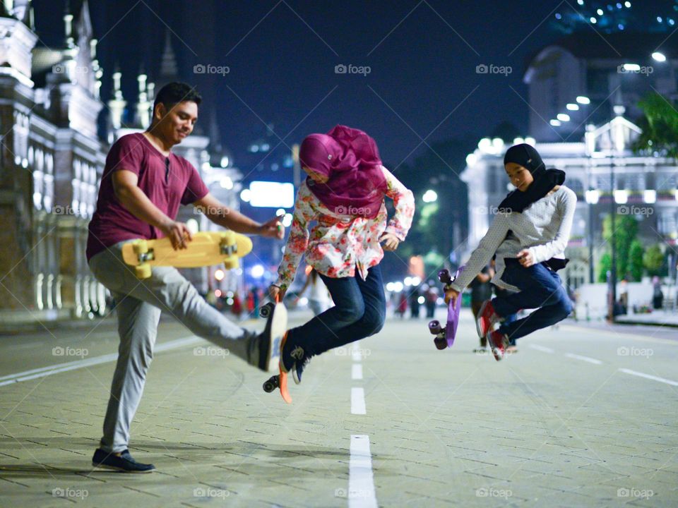 Siblings enjoying skateboarding in the city at night