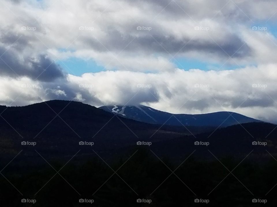 White Mountains of NH with brilliant white clouds lingering above.