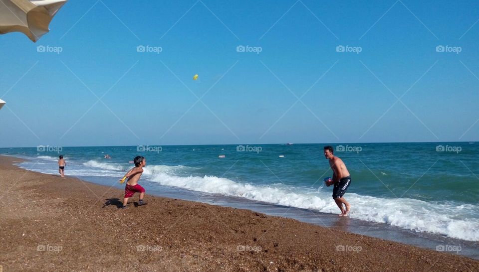 me and the boys enjoying a hot summer day at the beach in Antalya turkey. One is running to the water I'm splashing while the other is running away from it.