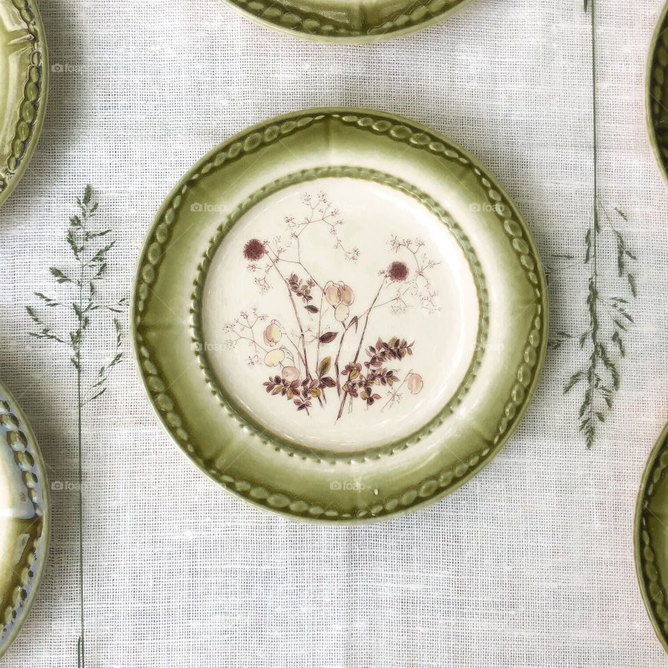 Green ceramic plate with herbal ornament for traditional herbal cake