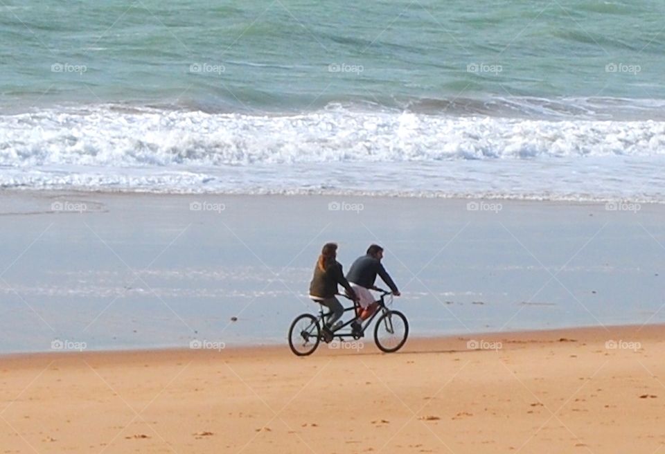 water mean biking on the beach together. Spain