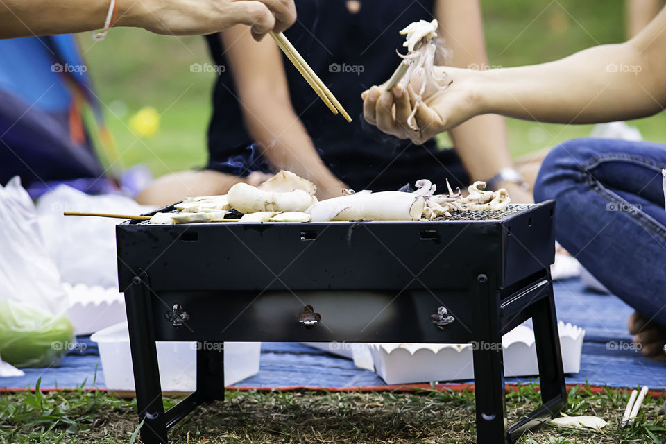 Fresh squid and mushrooms on the grill grate steel.