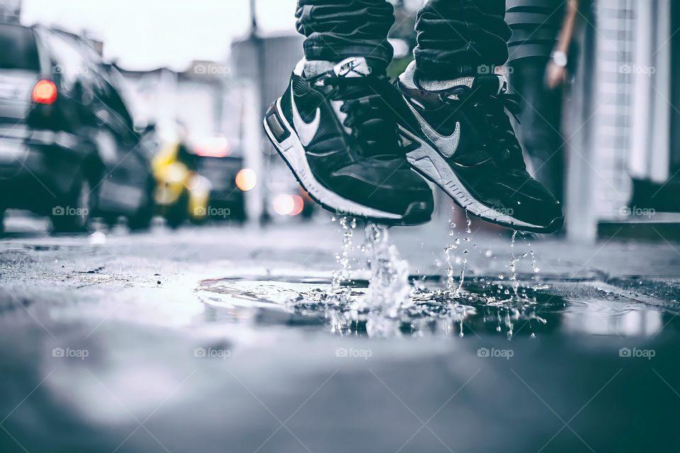 Shoes in Puddle. Low section of man jumping in puddle on city street.