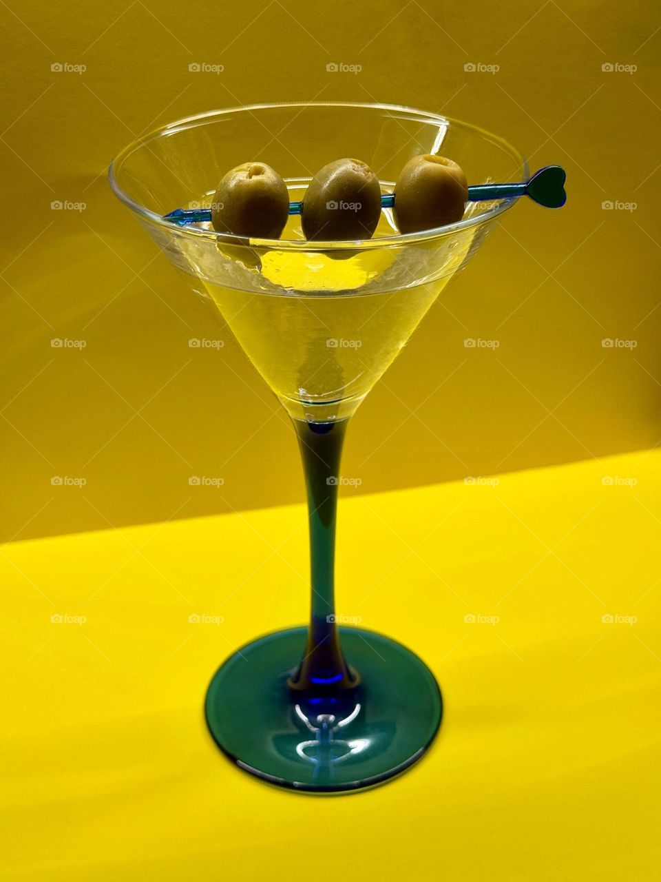 Closeup of Martini glass with olives on the yellow background 