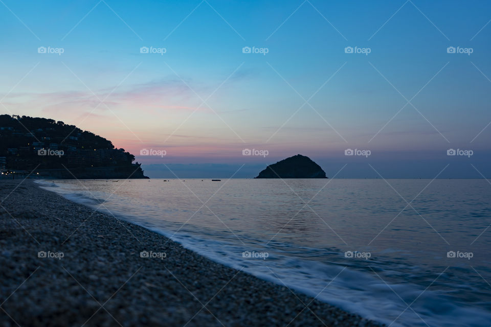 Sunrise over the sea. The sun rises from behind the peninsula and passes from the islet next to it.

Wonderful colors are created, including purple, red, orange, blue.