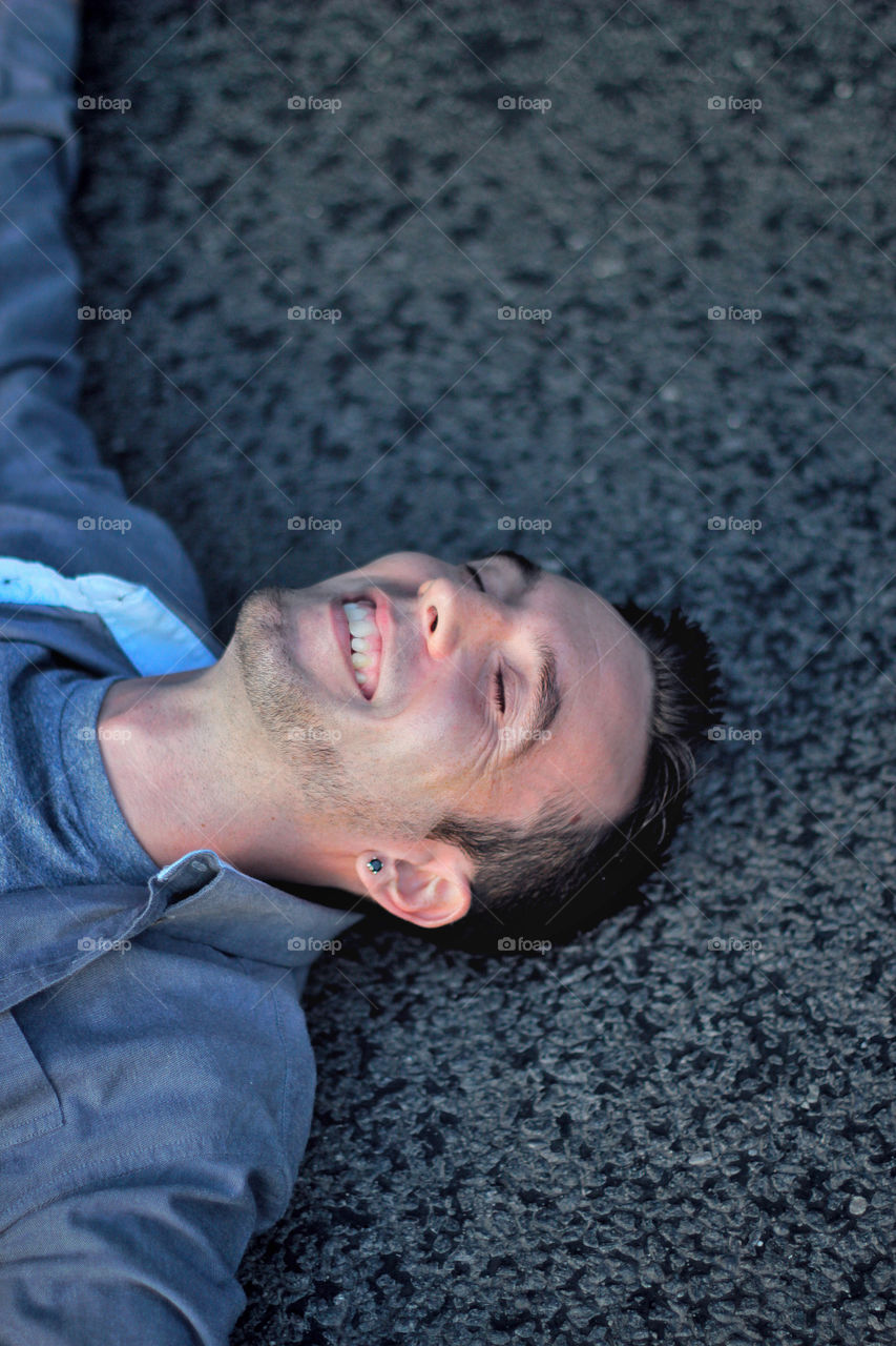 Young man laying on the road smiling 