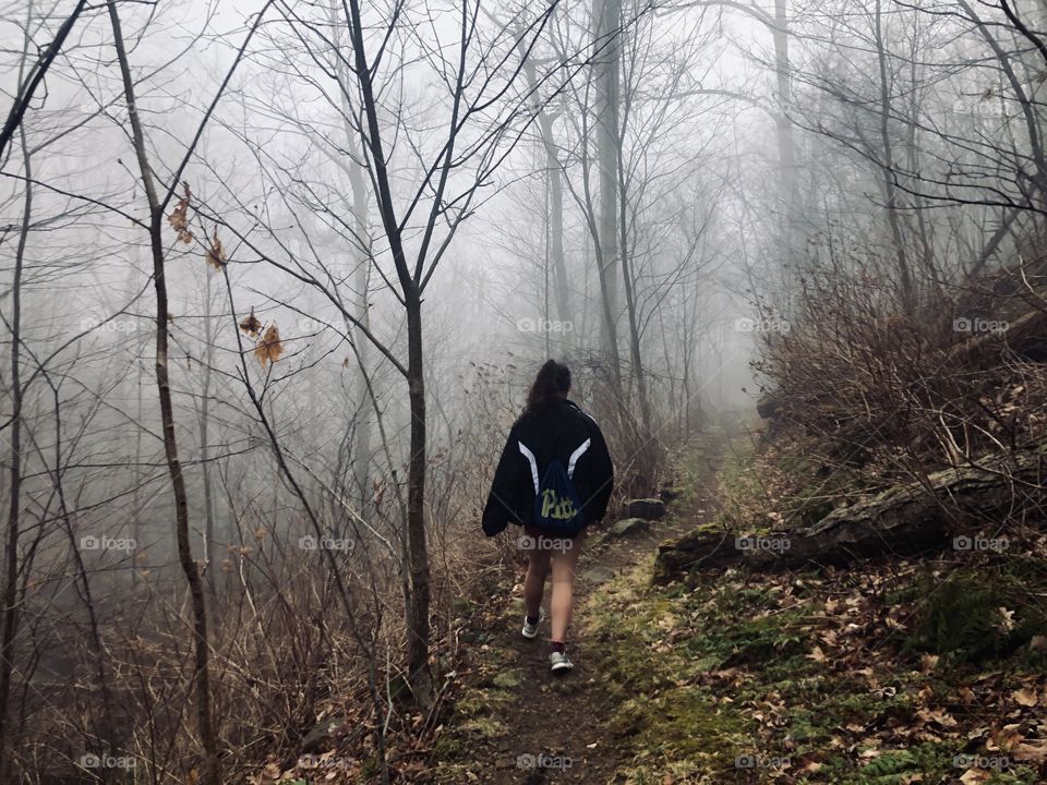 girl walking through a foggy, creepy, ominous mountain