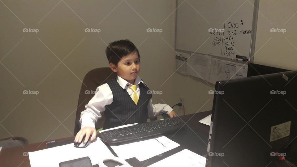 kid wearing suit sitting at office in front of computer