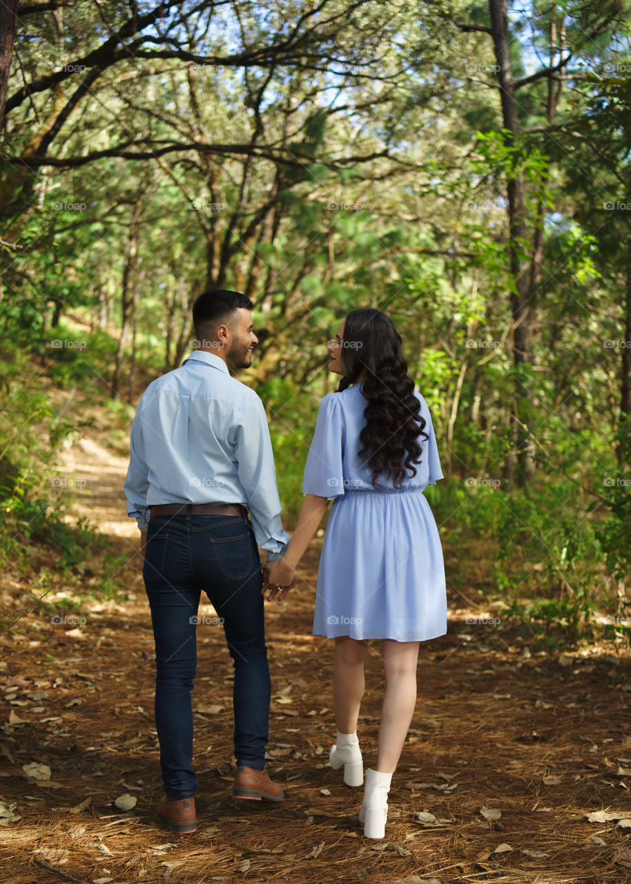 Couples of young people walking in middle of the forest while looking into their eyes, in a sunny day.