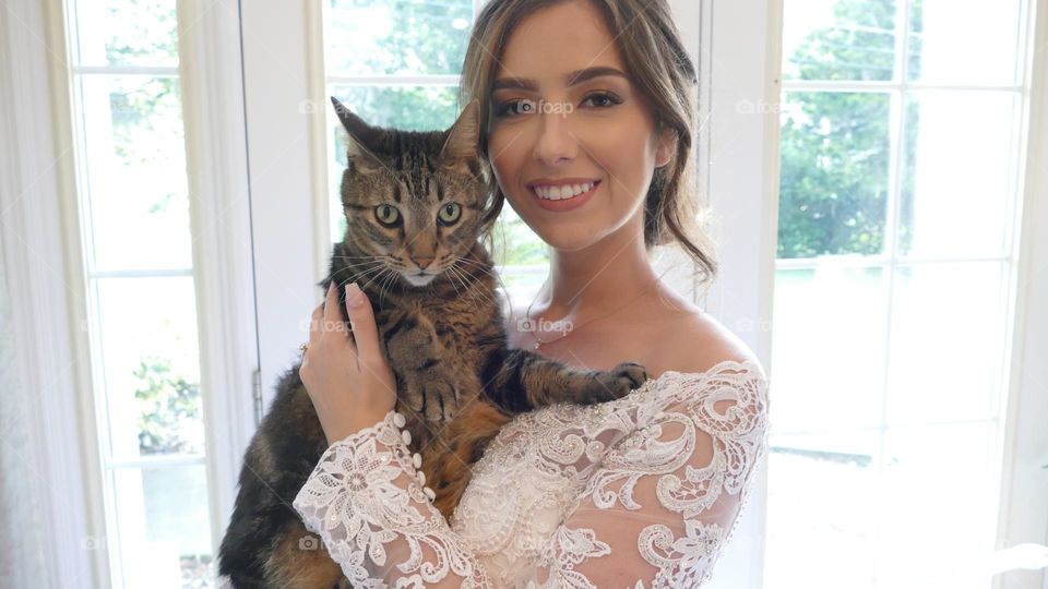 Bride in wedding dress saying goodbyes to her cat on her wedding day