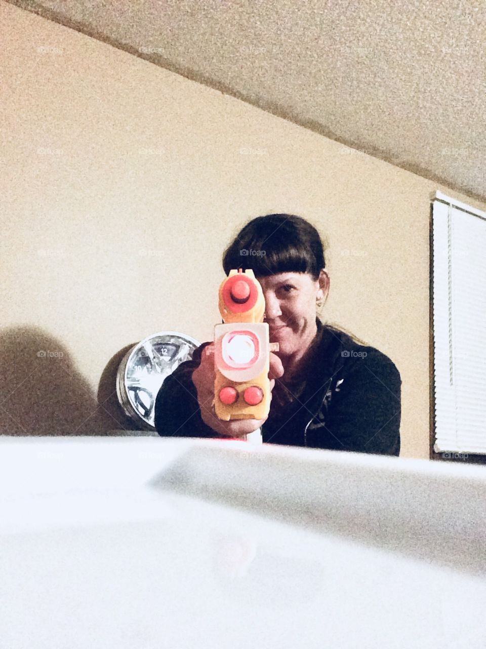 With her target locked in with a laser sight, a woman smirks as she gently squeezes the trigger on a well loaded nerf gun. 