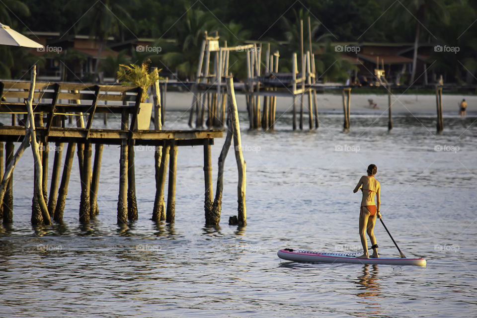 Tourists on surf boards in the sea Background  wooden bridge at Koh Kood, Trat in Thailand.