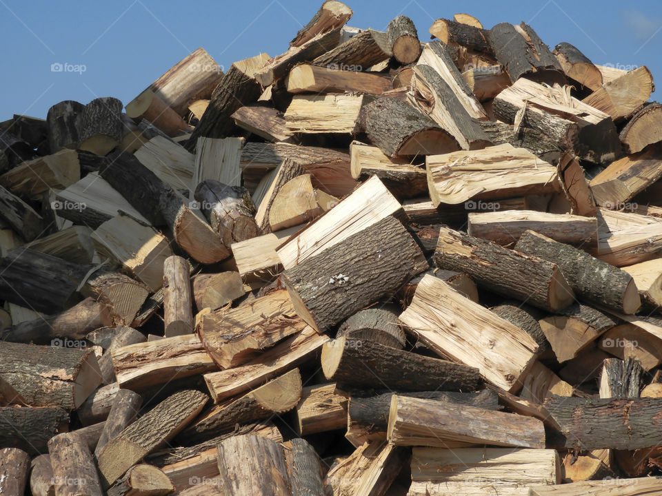 Large pile of firewood stacked and ready to be burned. May also be used as a background or texture.