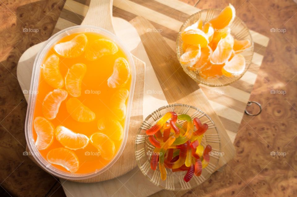 Delicious orange jelly with tangerine slices in a container and jelly worms.