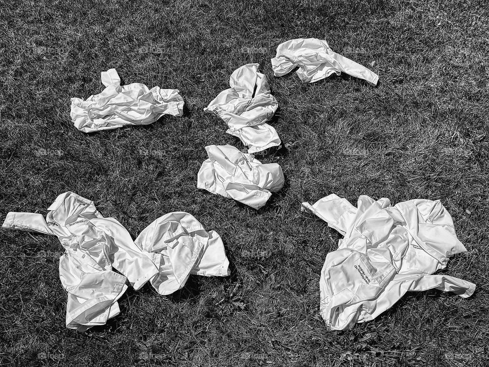 Black and white image of white coats on the grass, doctors graduating from residency, throwing doctors white coats 