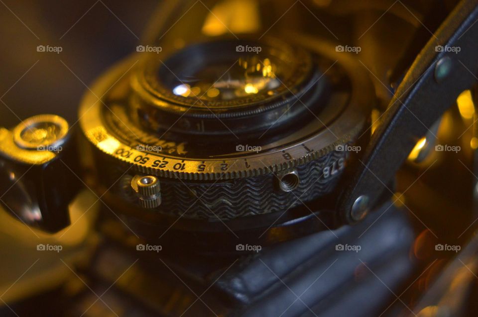 close up photo of an old mechanical photographic device. antique metal lens with focus and iris adjustment ring.