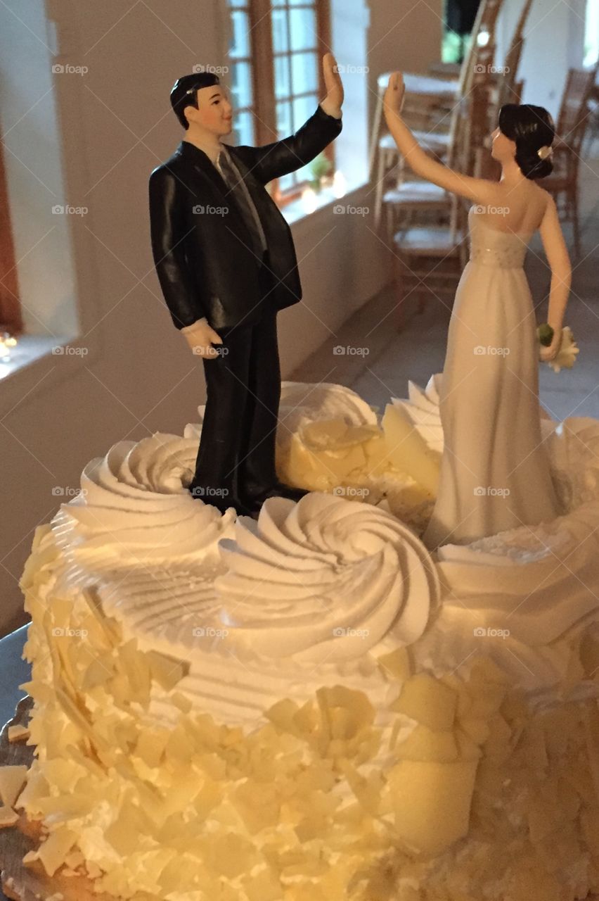 Non-traditional wedding cake topper with the bride and groom giving each other a high five. 