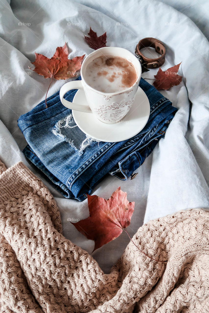 White mug of coffee on the bed