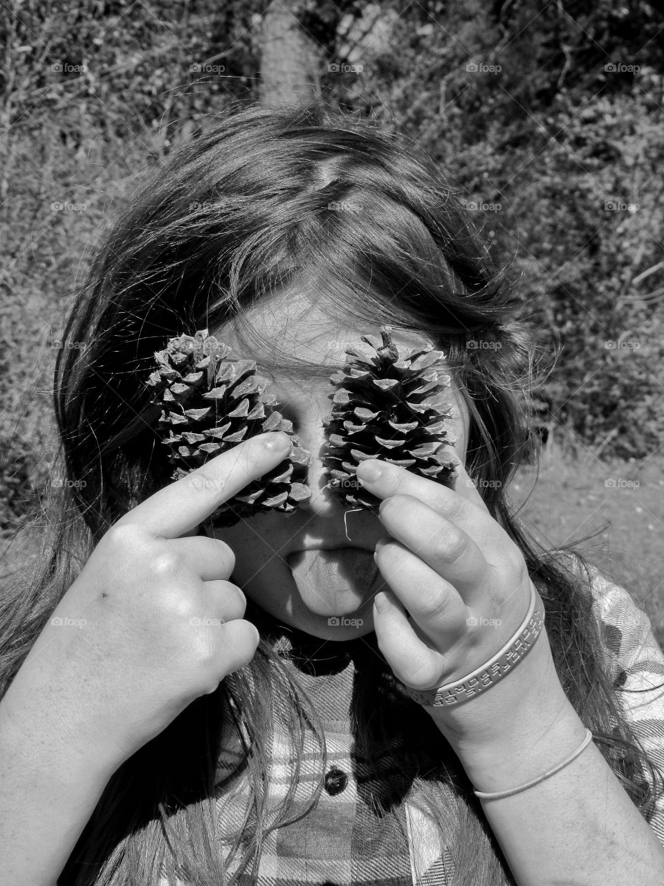 funny girl holding pine cones over eyes outdoors