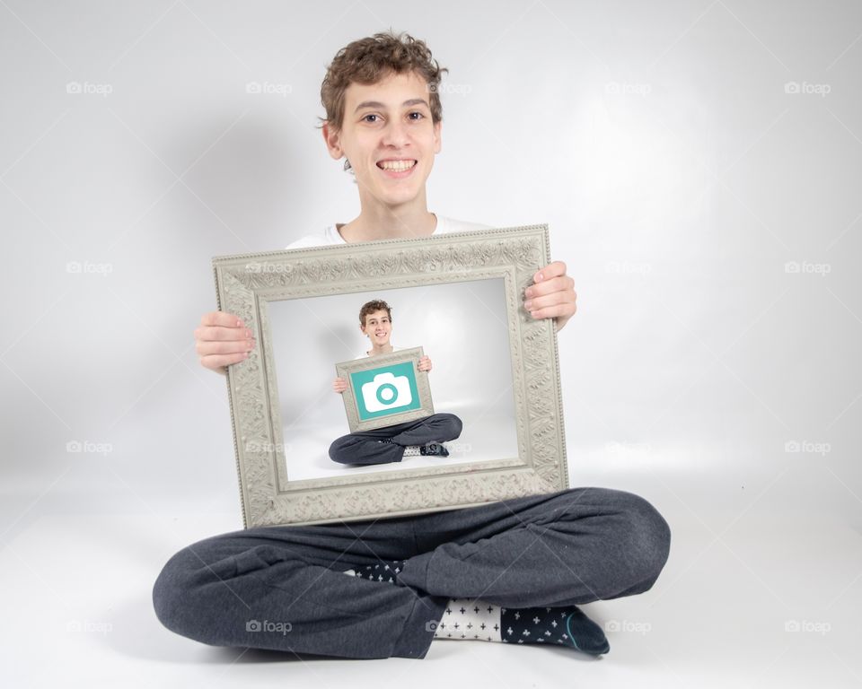 Boy on a White Background holding a frame in a frame picture with the Foap logo