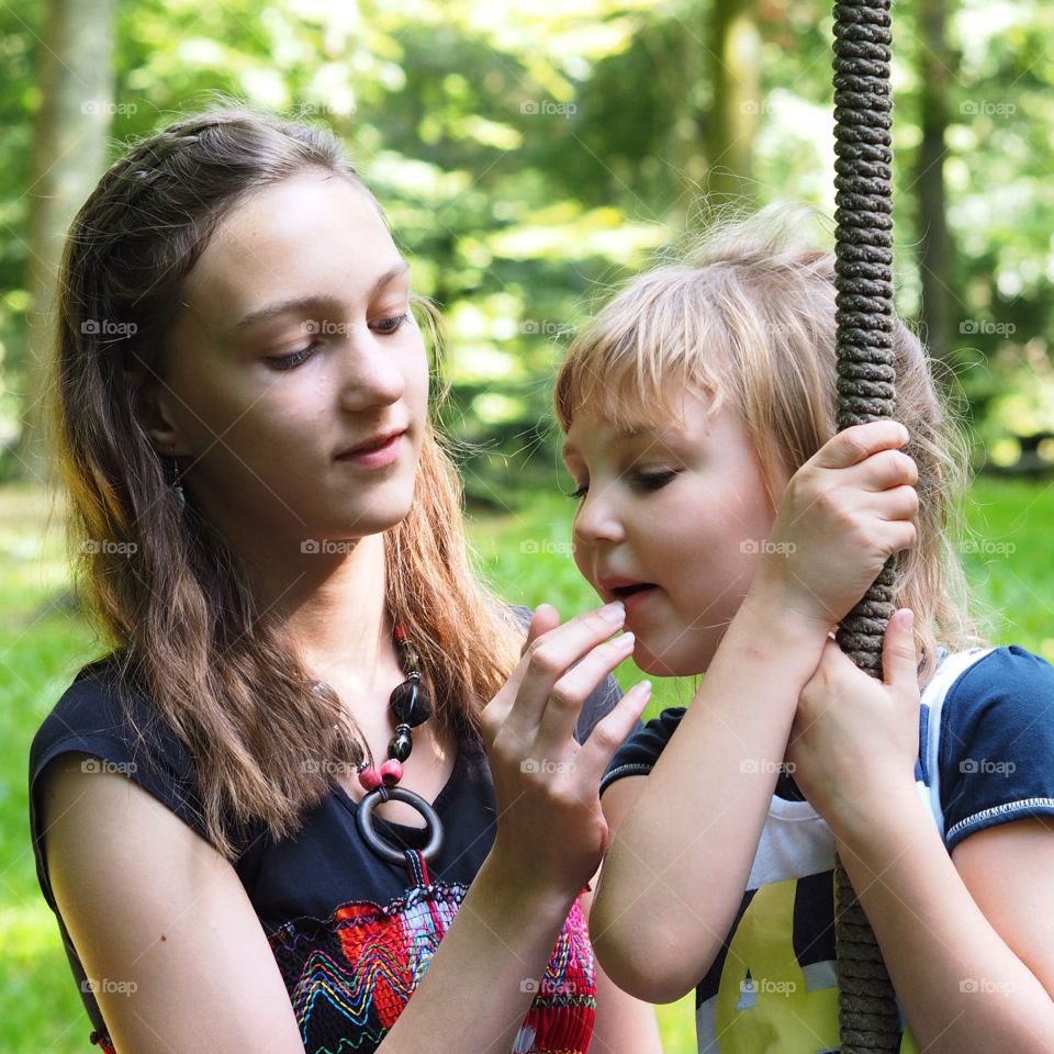 Kids sharing raspberries. Two girls, the older one feed the younger a raspberry.