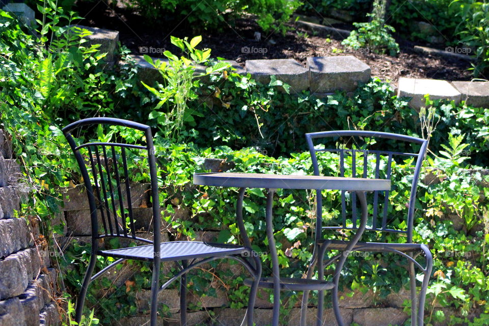 This is a picture of metal table and chairs outside on a beautiful sunny spring day.