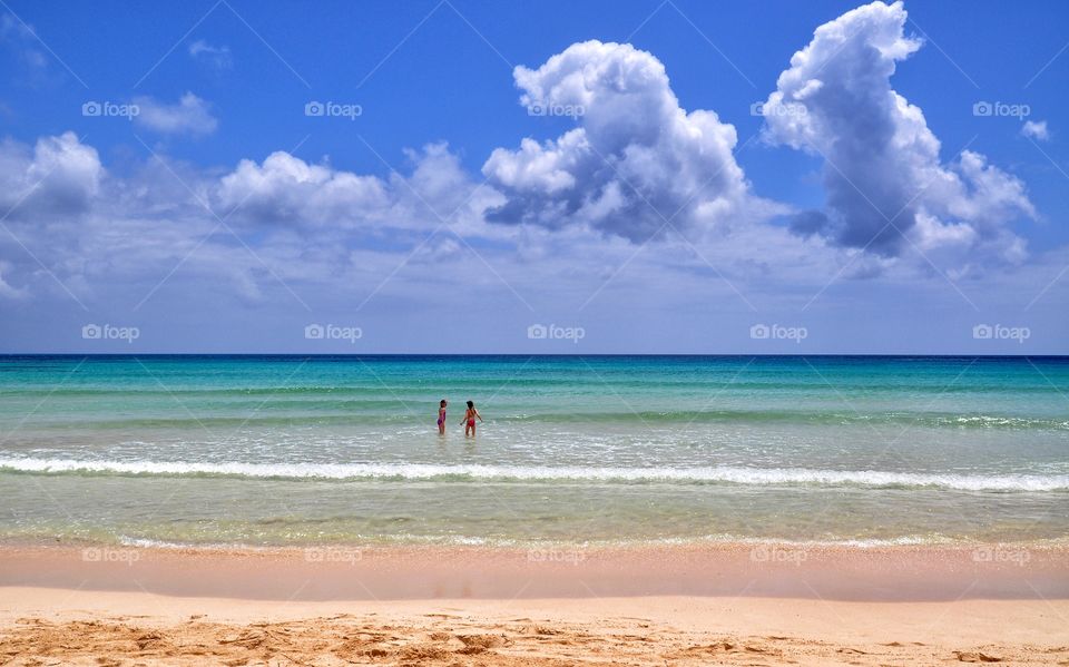 amazing corralejo beach with two people in turquoise transparent water of the atlantic ocean - fuerteventura canary island in spain