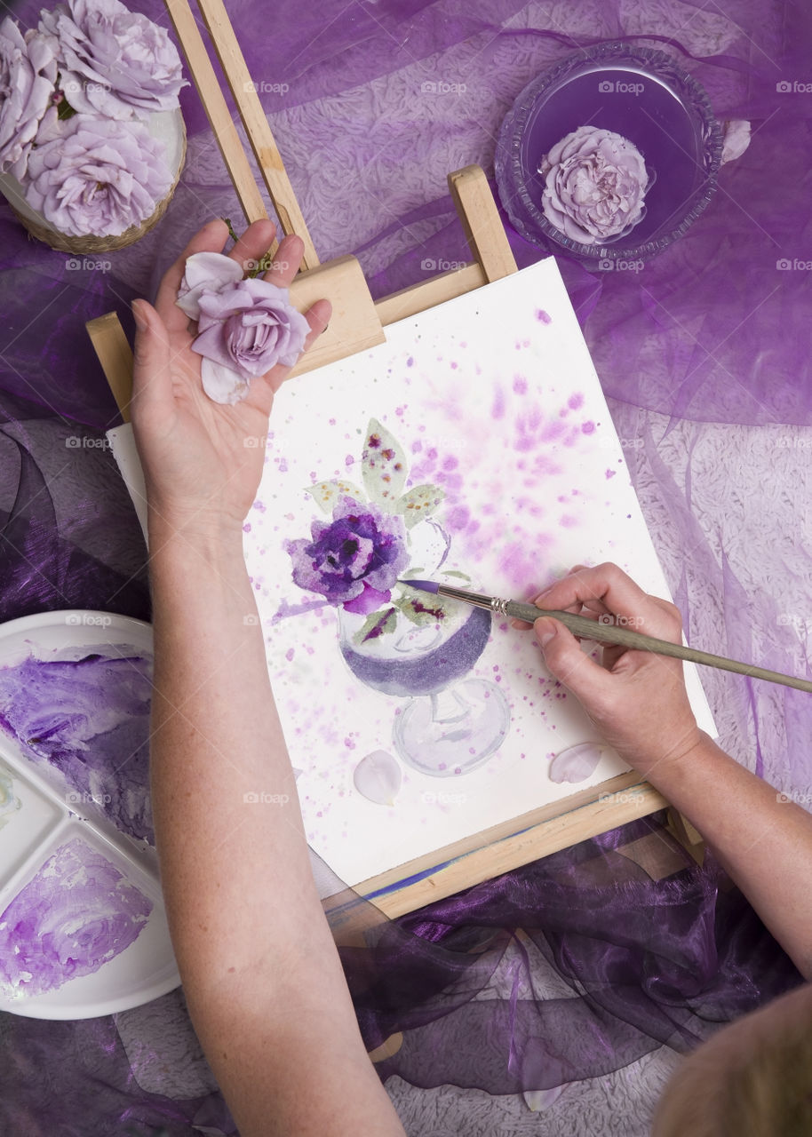 the girl draws a sketch of an ashy purple rose and holds a living rose in her hand