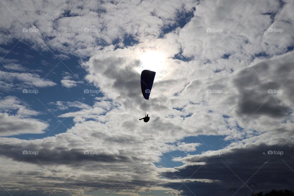 Paraglider up in the cloudy sky