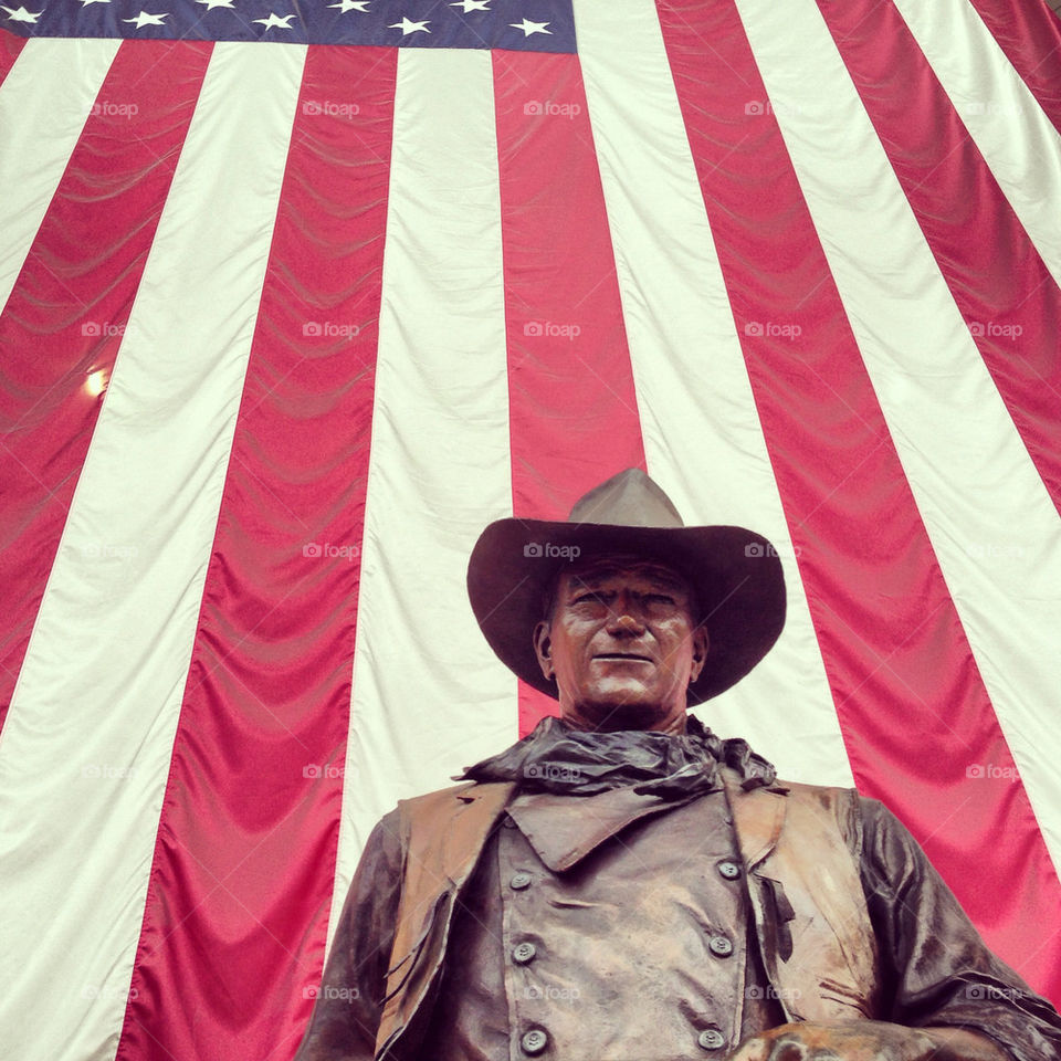 John Wayne statue in front of American flag at John Wayne airport.