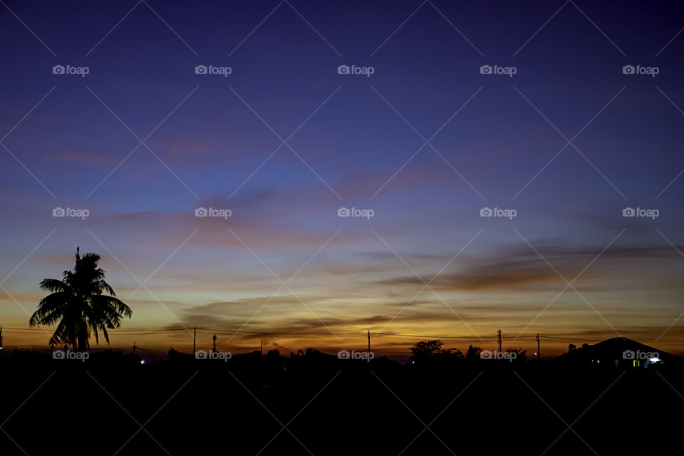 Beautiful light of Sunset with clouds in the sky reflection behind the building and trees.