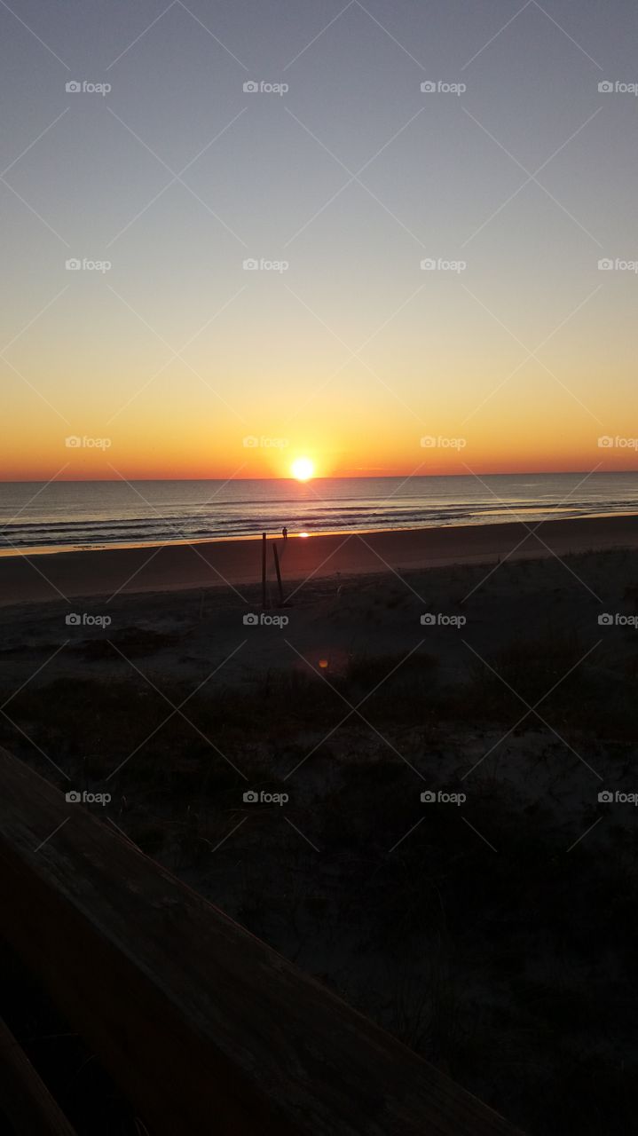 I captured this photo of the sunrise on the Atlantic Ocean in Jacksonville Beach Florida. This man is walking his dog in the early morning Sunrise.
Look at the glow in the Eastern skies.