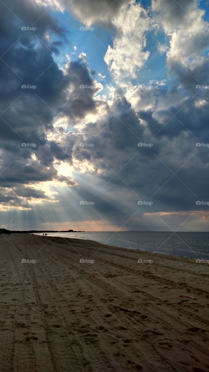 Sunlight streaming through clouds over the beach
