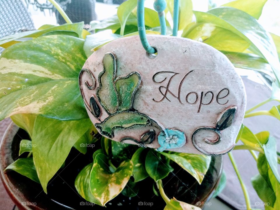 outdoor potted plant with an inspirational stone sign that reads the message 'hope'