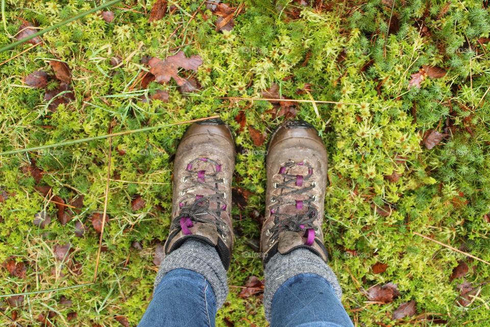 Boots standing up on moss and leaves. 