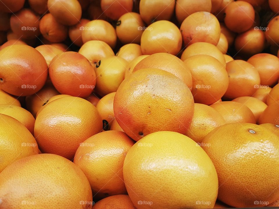 Orange grapefruits stacked and grouped on display shelves for sale