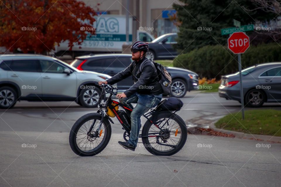 Young man is riding an electric bike on a street of a big city