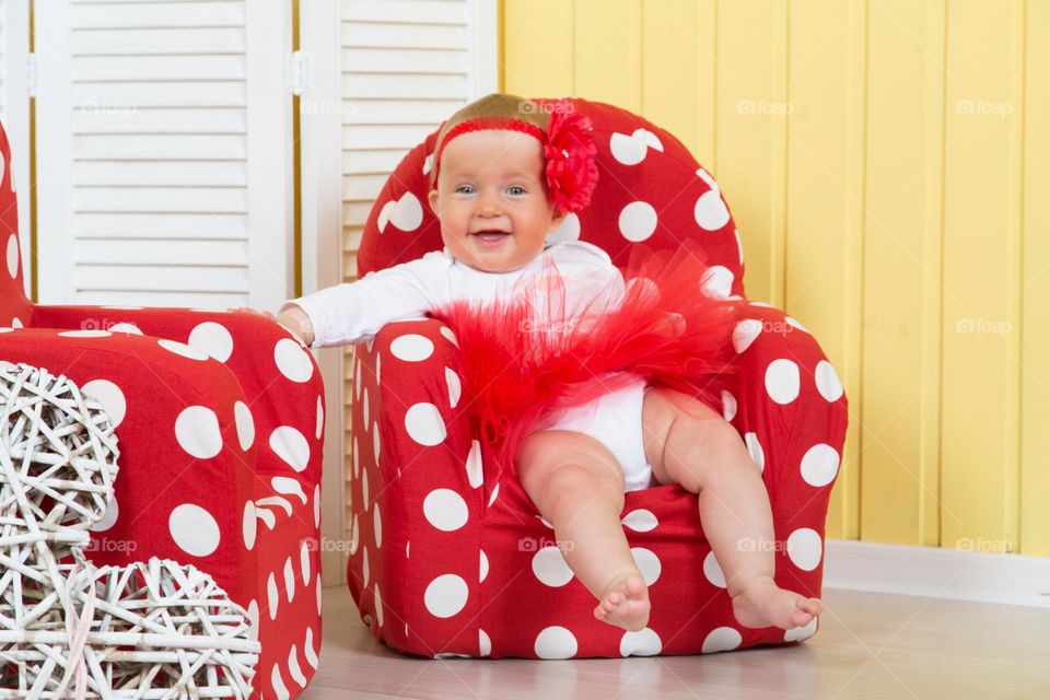 Happy baby sitting in red chair 