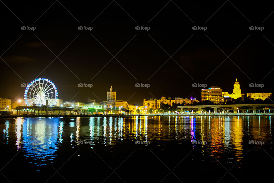 Malaga port by night, Spain. A shot across Malaga's port at night, mixing old and new architecture in glittering reflections in the Mediterranean Sea
