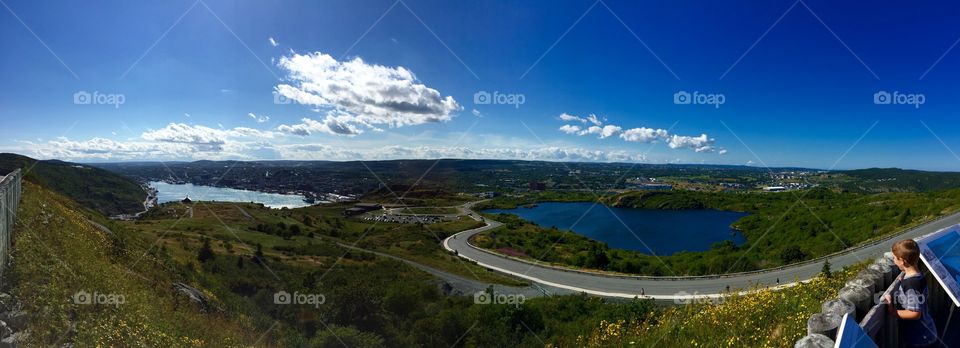 Panoramic shot of St. John's, NL from atop Signal Hill with a young boy looking out at the city. 