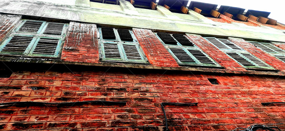 Captured an old house with vintage styled wooden windows, red coloured brick wall,faded color.